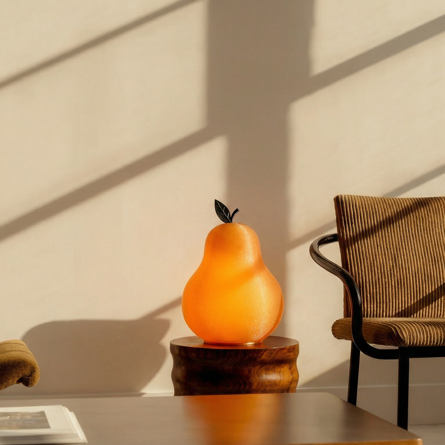Decorative pear-shaped lamp on a table with a chair and open book in a softly lit room.